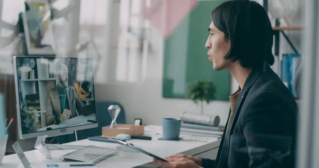 A professional engaged in a video conference in a modern office setting. Asynchronous collaboration
