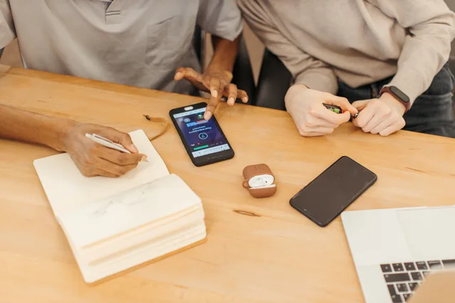 Teamwork at a table using smartphones, notebooks, and laptops to collaborate in an office setting. Collaboration software adoption