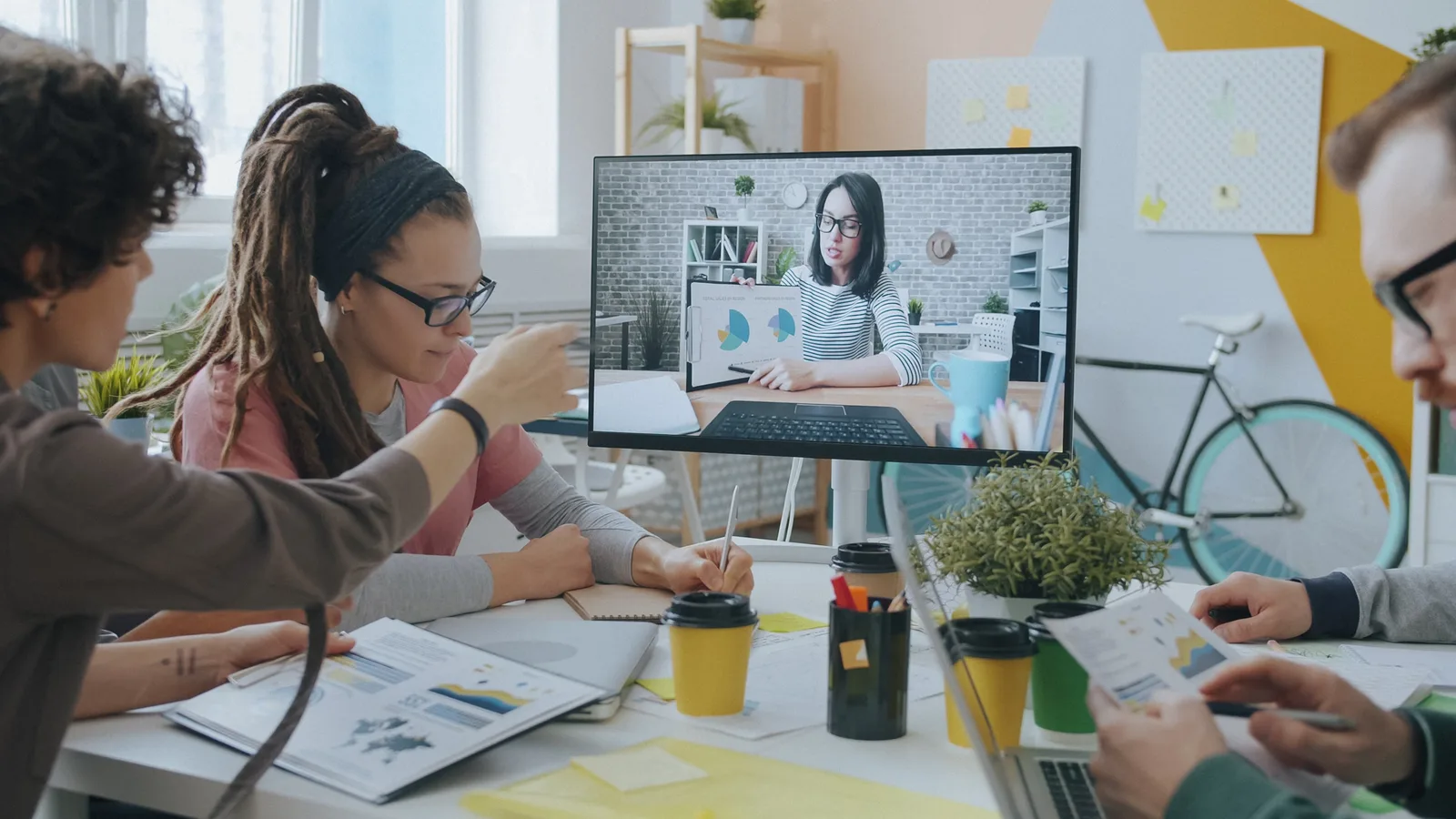 Young professionals collaborate during a video call in a creative and modern office setting.