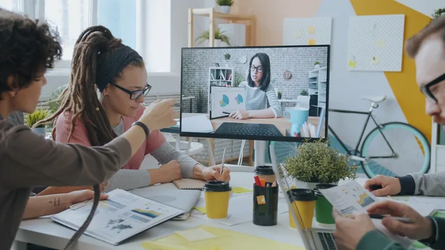 Young professionals collaborate during a video call in a creative and modern office setting. Reducing collaboration tool overload